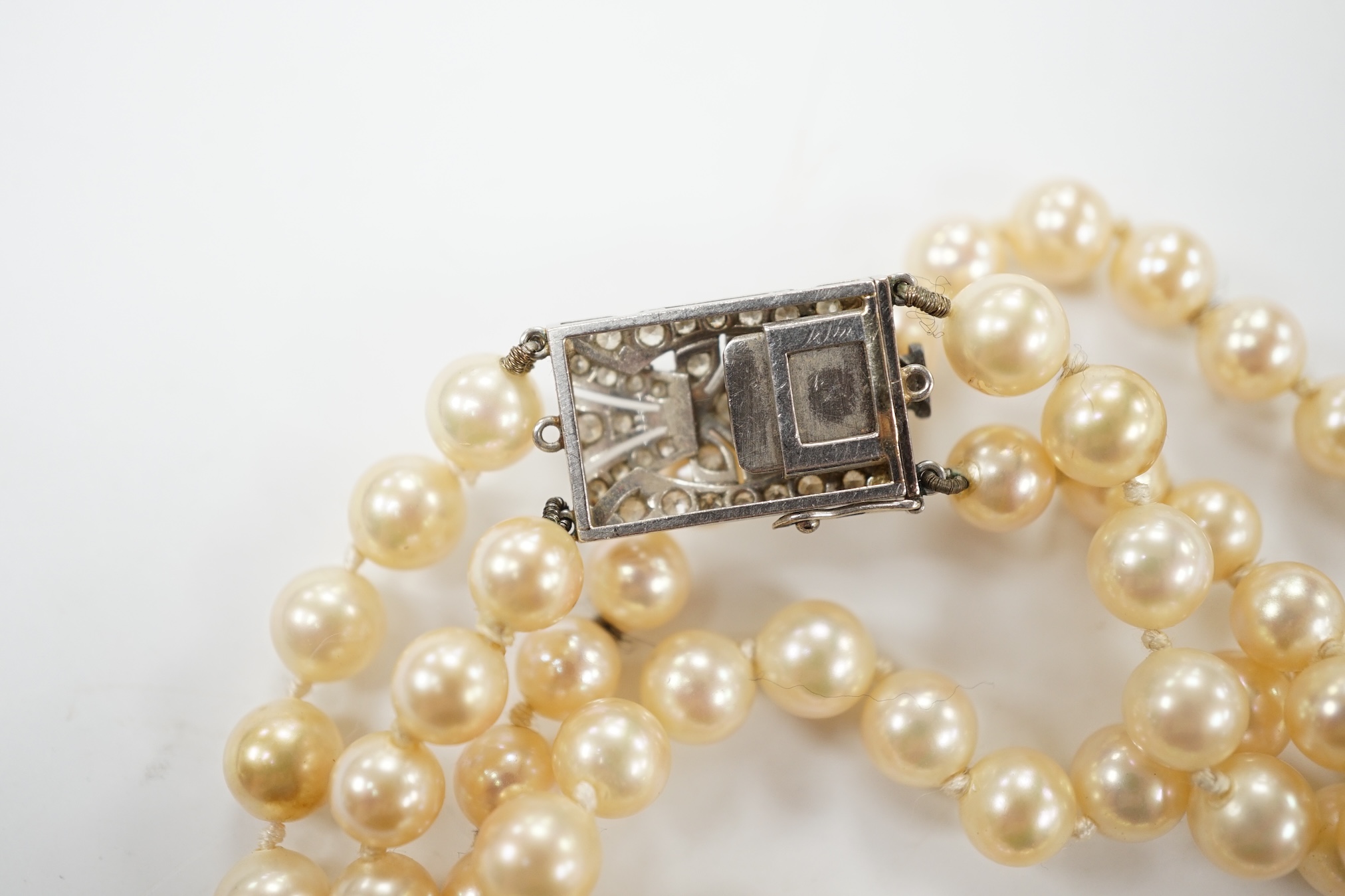 A double strand simulated pearl necklace, with diamond cluster set white metal clasp, 90cm. Condition - fair